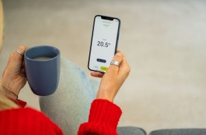 Smart phone being held with smart thermostat app